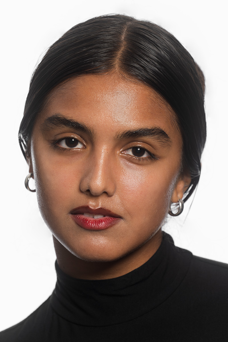 Close studio headshot of a woman in a black turtleneck against a white background