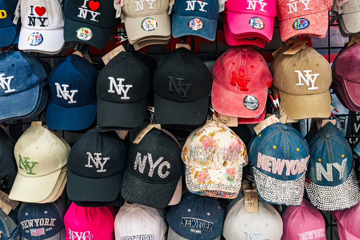 Colorful New York souvenir baseball caps arranged across a street vendor's display