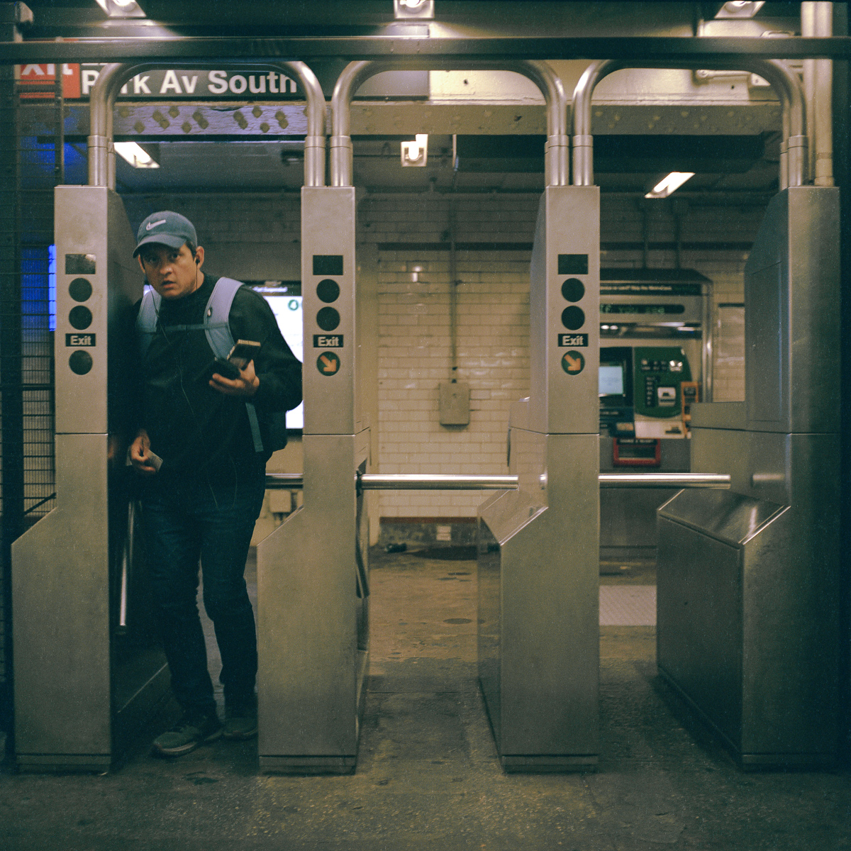 A person with a backpack passing through a metal subway turnstile