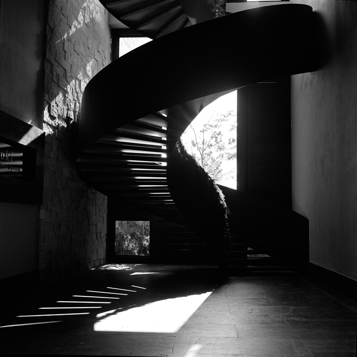 A dark spiral staircase and bands of sunlight falling across the floor