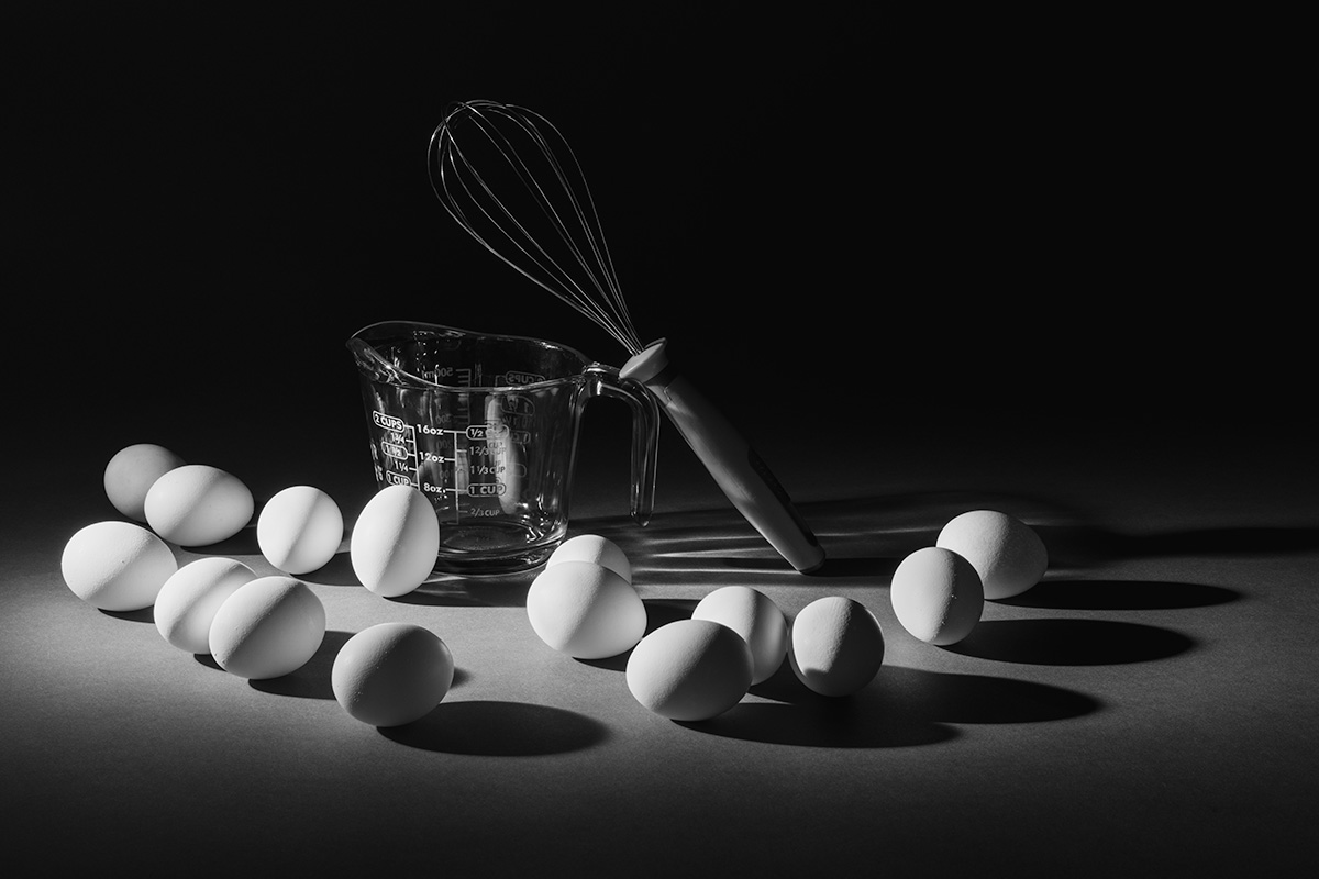 Still life photograph of eggs and a measuring cup