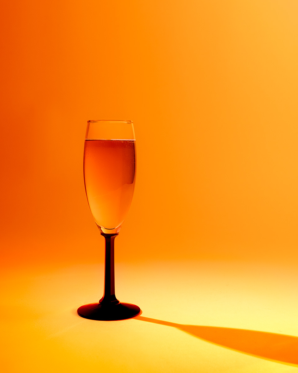 Still life photograph of orange glass with a cast shadow